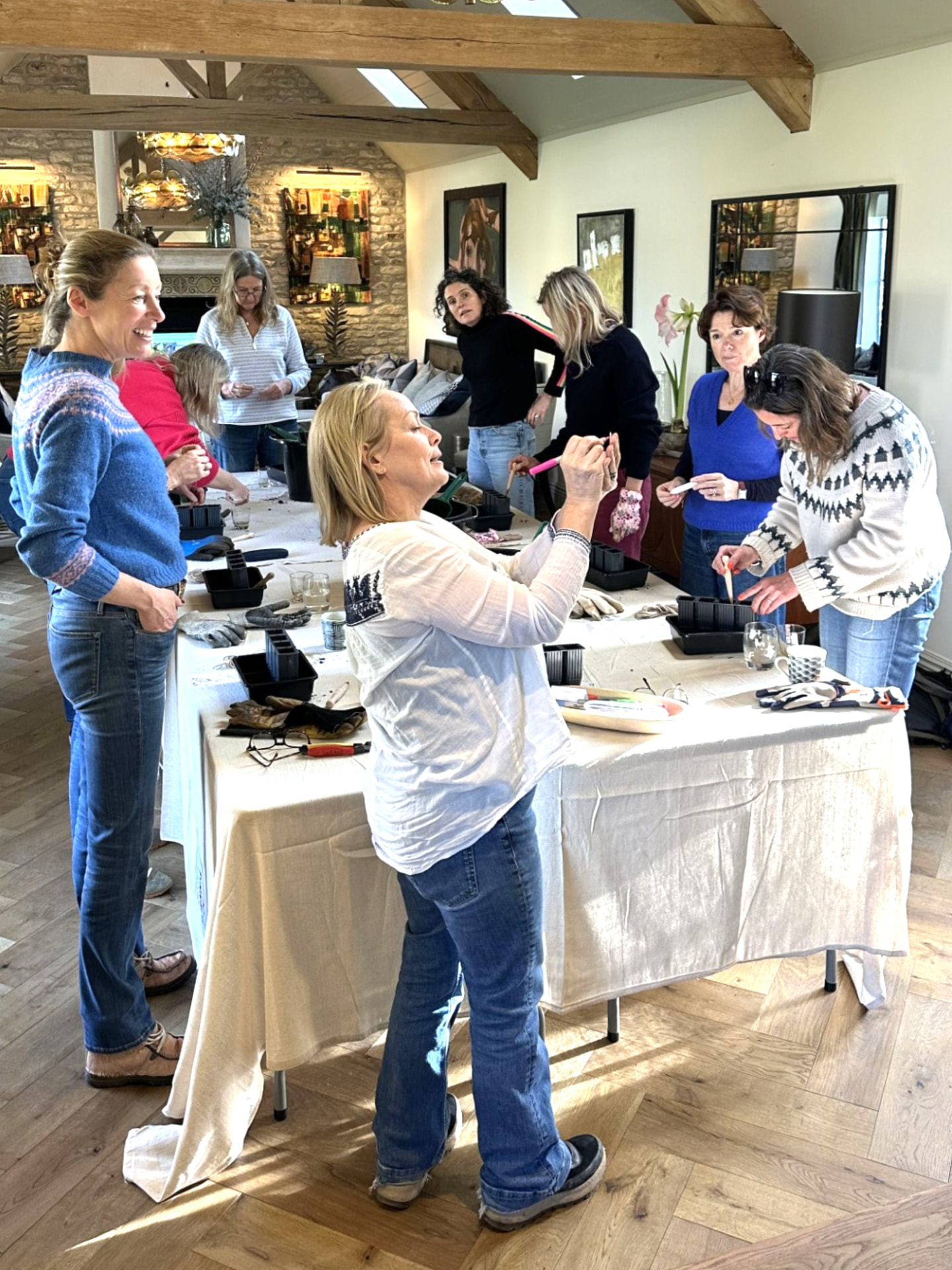 Garden Club guests potting up plants together around a long linen-covered table