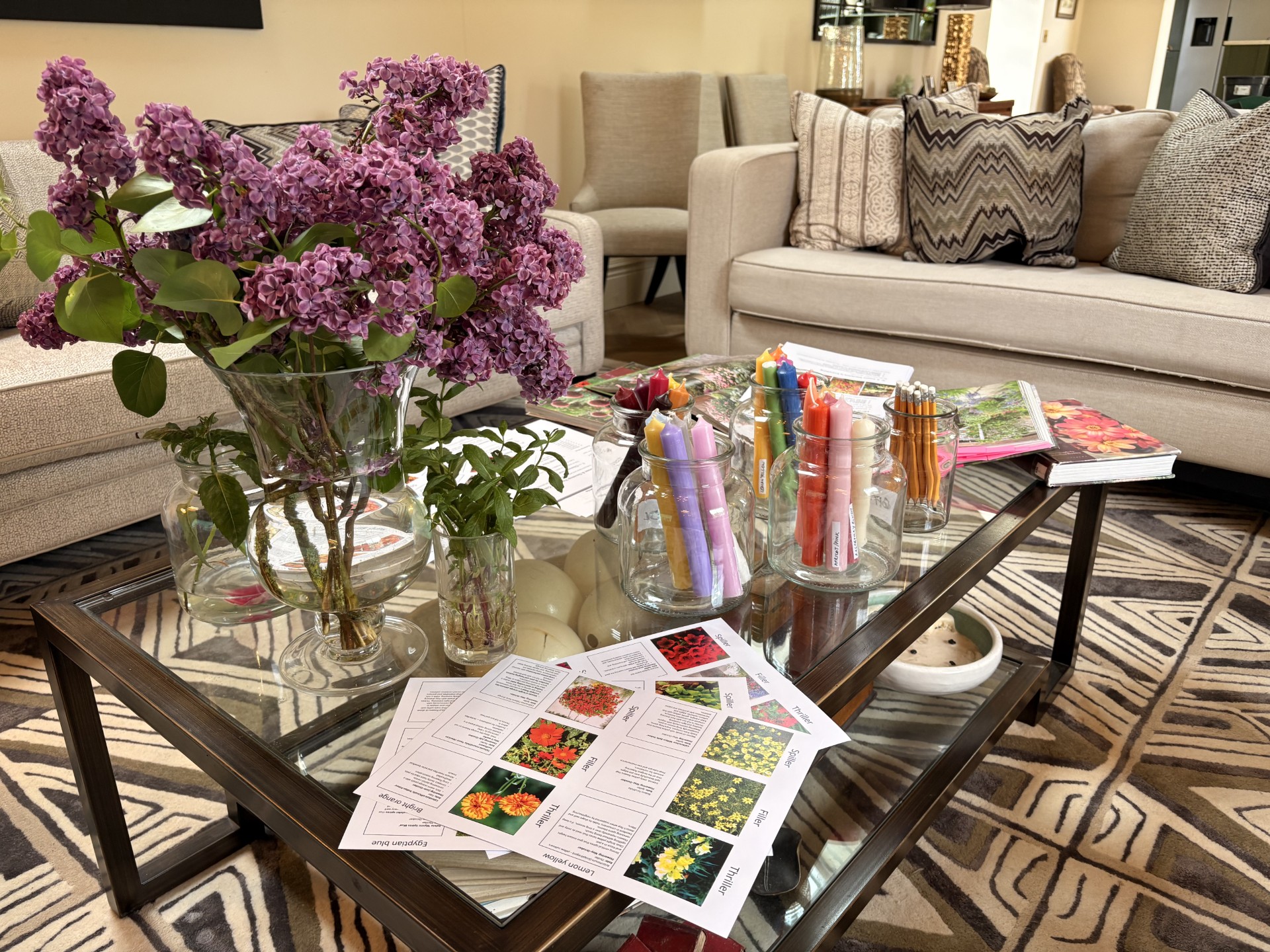Sitting room coffee table set up for a garden workshop with lilac in a vase, herb cuttings, candles and colour planting sheets