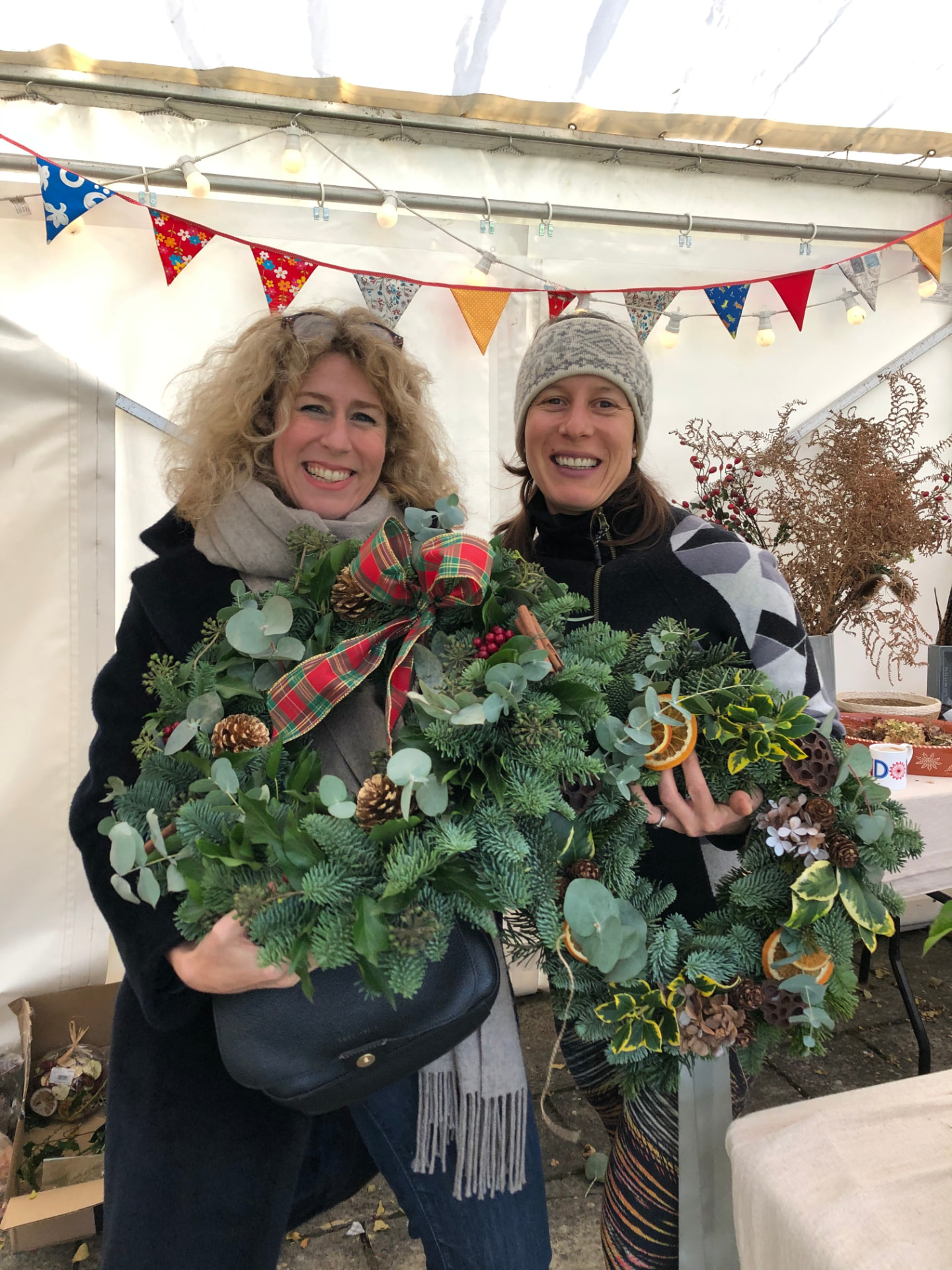 Two guests holding their finished Christmas wreaths